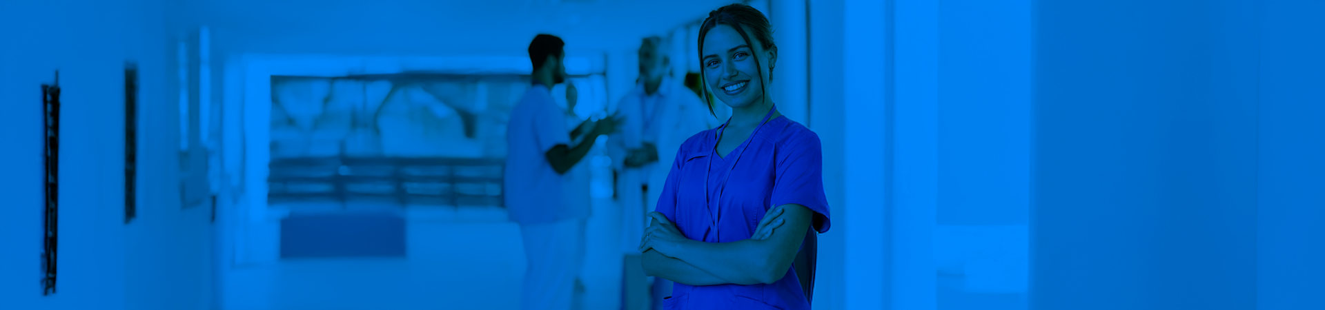 Infermiera sorridente in corridoio ospedaliero.